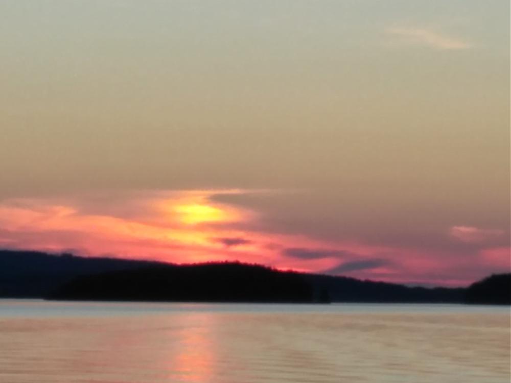Kuvassa järvimaisema ja punertava auringonlasku.