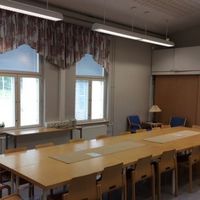 Neulamäen kirkon kokoustila Kokoustilassa pitkä pöytä jonka ympärillä tuoleja. Taustalla ikkunat.