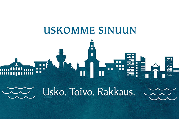 Kaupunkisiluetti, jossa Tuomiokirkko risteineen nousee korkeimmalle. Kuvassa tekstit: Uskomme Sinuun ja Usk...