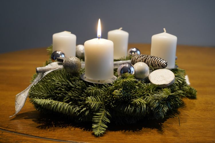 Neljä adventtikynttilää, joissa yhdessä liekki havu seppeleessä. 