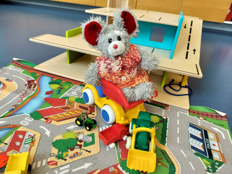 Leikkitreffit Harmaa nalle automatolla istumassa.