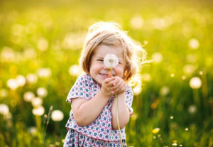Pieni lapsi katsoo iloisena kesän kukkaa. 