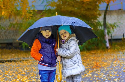 Poika ja tyttö sateenvarjon alla syksyllä