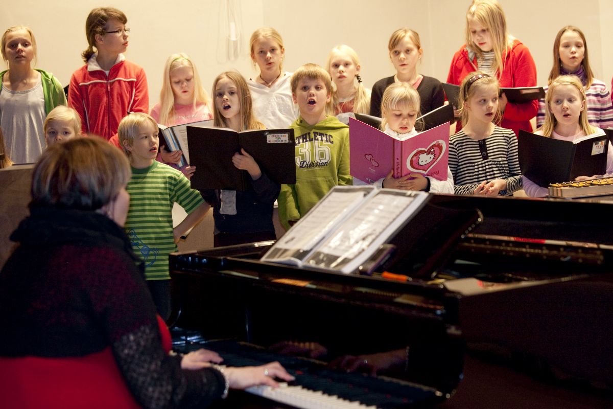 Lapsikuoro laulaa pianon säestyksellä.