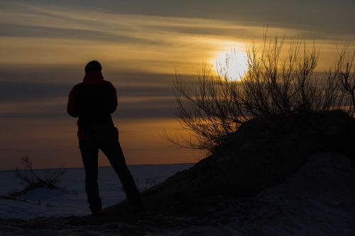 Mies katsoo auringonlaskua