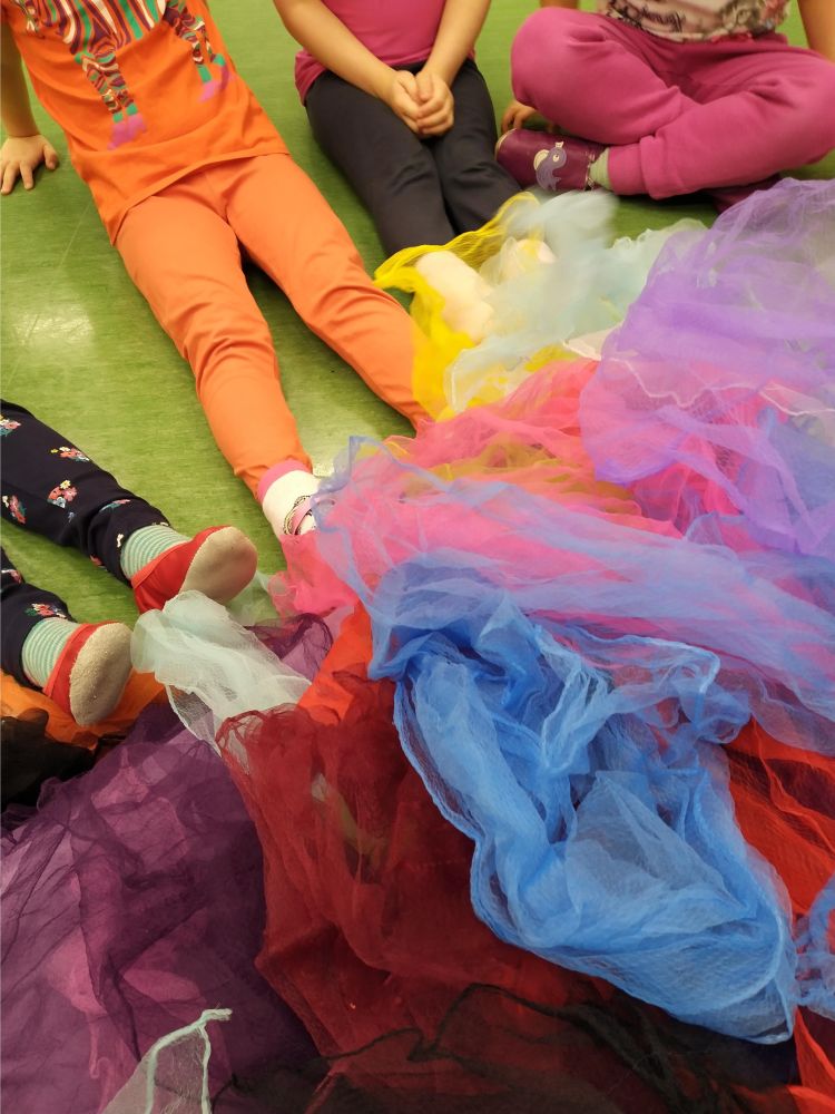 Lasten jalkojen juureessa värikkäitä huiveja.