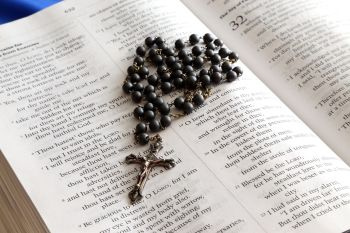 Avoinna oleva raamattu, jonka päällä on musta rukoushelminauha
