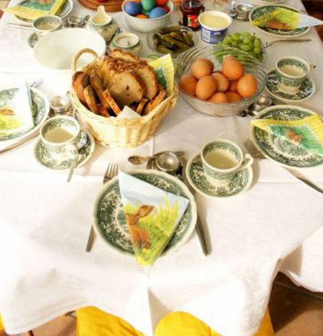 Pöydässä pääsiäisen astioita, leipää, kananmunia