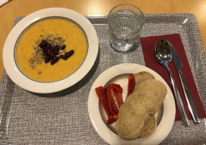 Tarjottimella lautanen jossa keittoa, leipä ja juoma