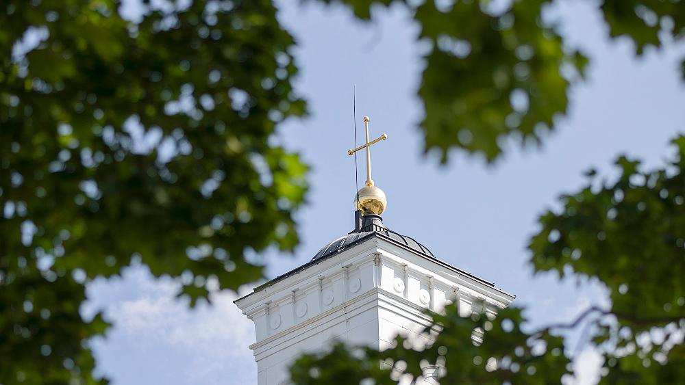 Puiden oksien välistä näkyy Tuomiokirkon torni ja kultainen risti.
