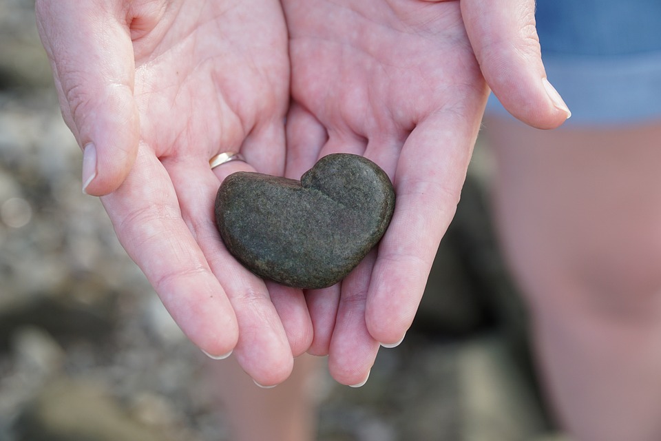 Sydämenmuotoinen kivi kädessä