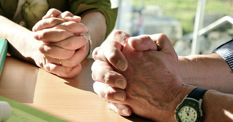 Pöydän päällä kahdet rukoilevat kädet.