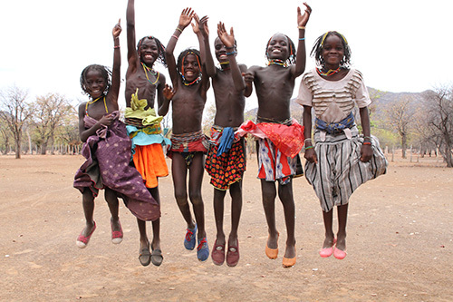 Angolalaisia lapsia, hyppäävät ilmaan ja nostavat kädet ylös.