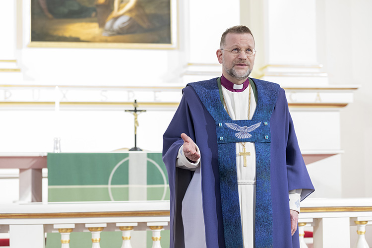 Piispa Jari Jolkkonen seisoo kirkossa, taustalla alttari.