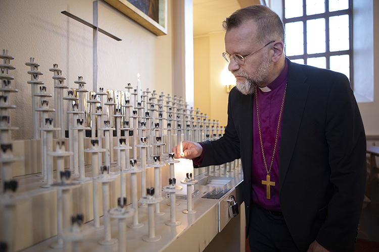 piispa sytyttää kynttilän