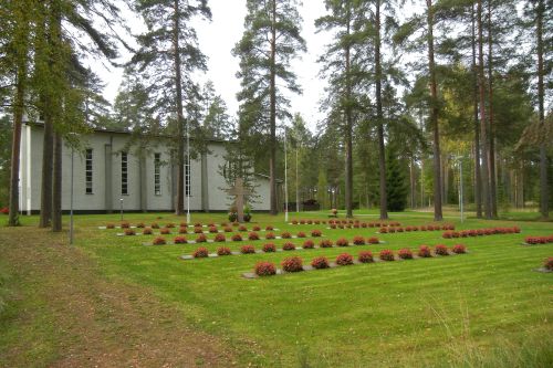 Punaiset kesäbegonia-istutukset kirkon vieressä olevalla sankarihautausmaalla.