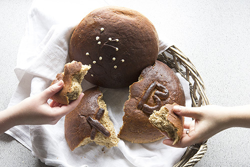 Kuvassa murretaan leipää yhdessä, kaksi kättä ja yksi leipä.