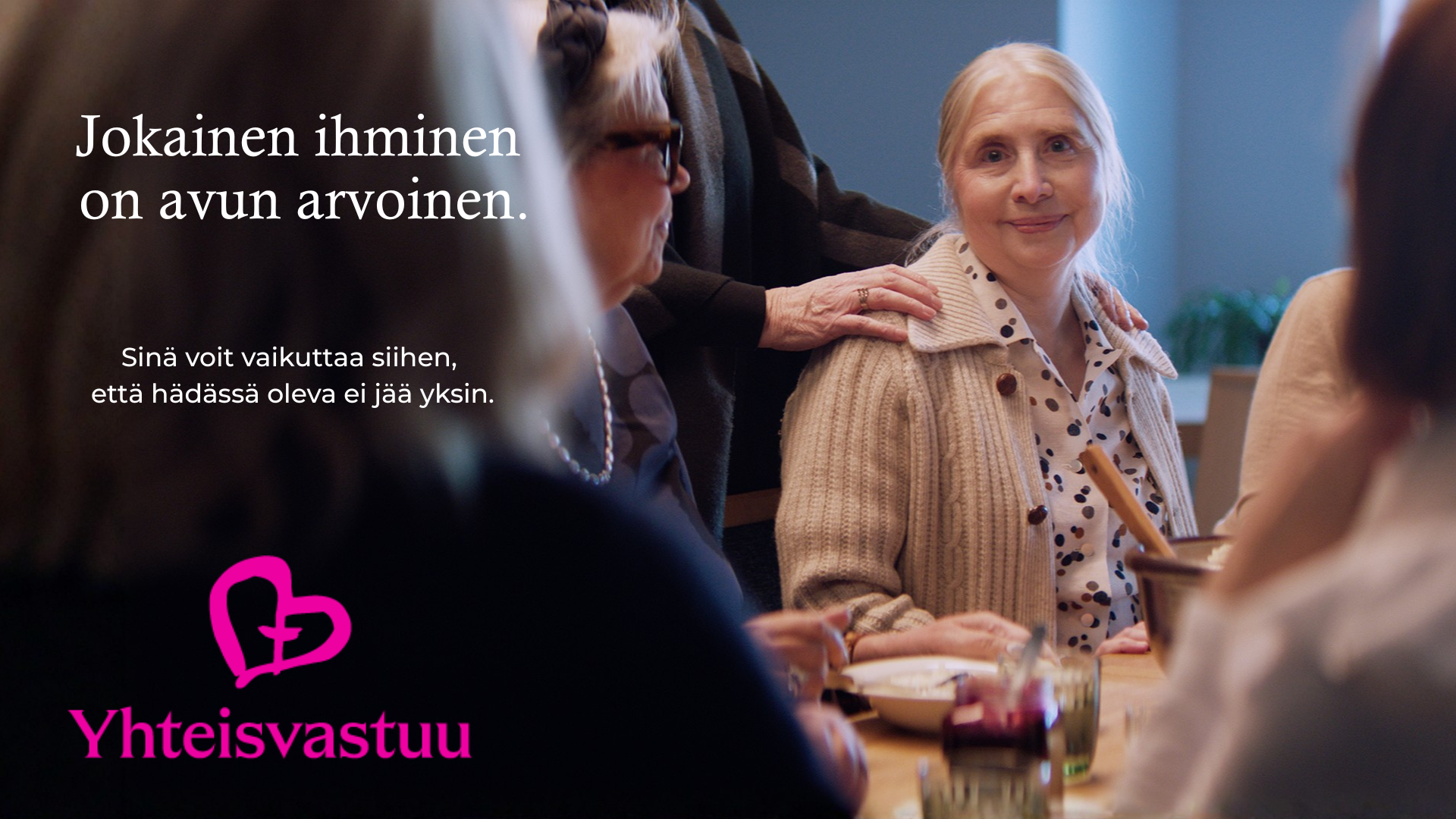 Ikääntynyt ihminen toisen ihmisen käsi olkapäällään.Teksti:Jokainen ihminen on avun arvoinen.Yhteisvastuu-logo