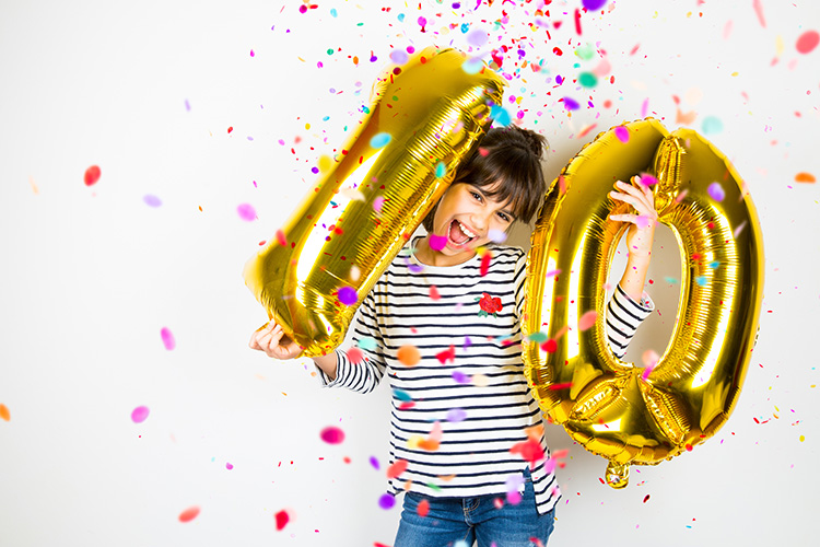 Lapsi pitää käsissään ilmapalloja, joissa on numerot 1 ja 0.